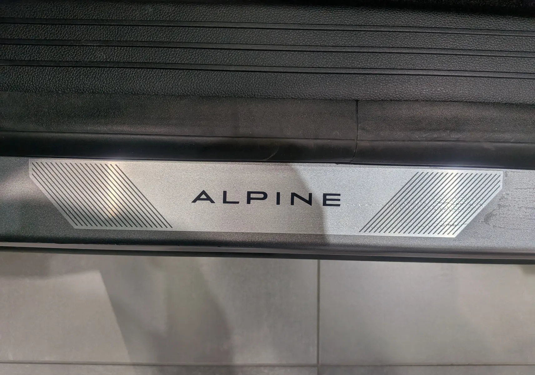 Gros plan sur la plaque de seuil de porte "ALPINE" du Renault Austral gris Schiste Satin version Esprit Alpine.