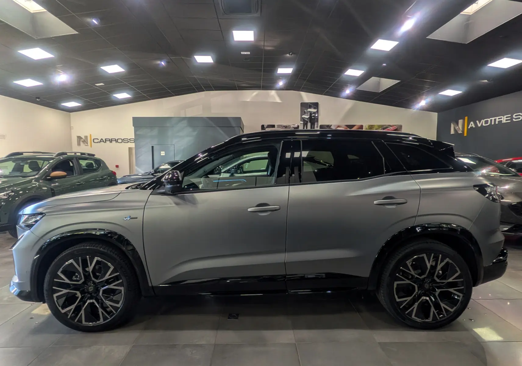 Profil droit du Renault Austral 2025 gris schiste satin avec toit noir et jantes noires distinctives en showroom.