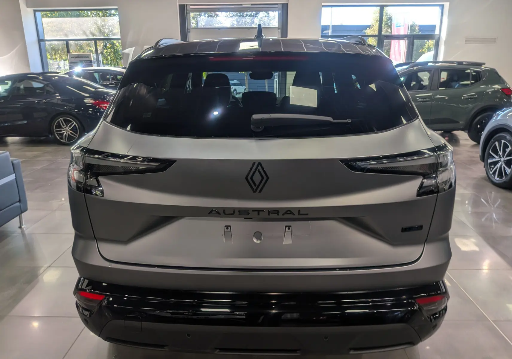 Vue arrière d'un Renault Austral gris schiste satin avec toit noir, mettant en valeur son logo et ses feux arrière fins.