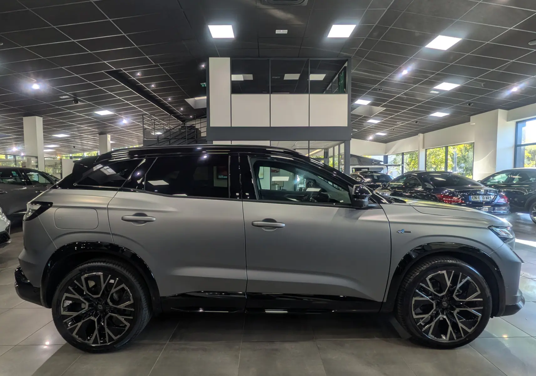 Renault Austral full hybride gris schiste satin avec toit noir, vue profil côté gauche en intérieur showroom.