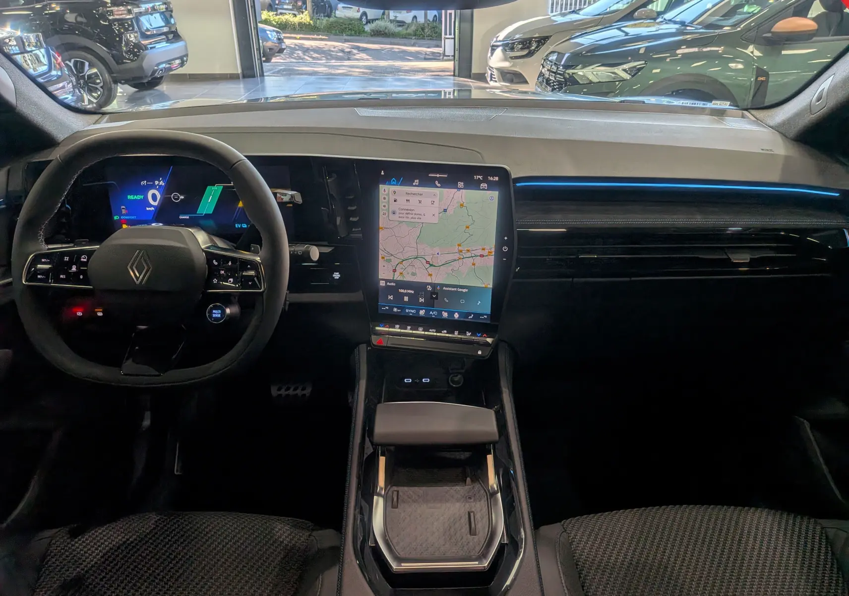 Vue intérieure avant du Renault Austral hybride 2025, tableau de bord moderne avec écran tactile vertical et éclairage bleu fin.