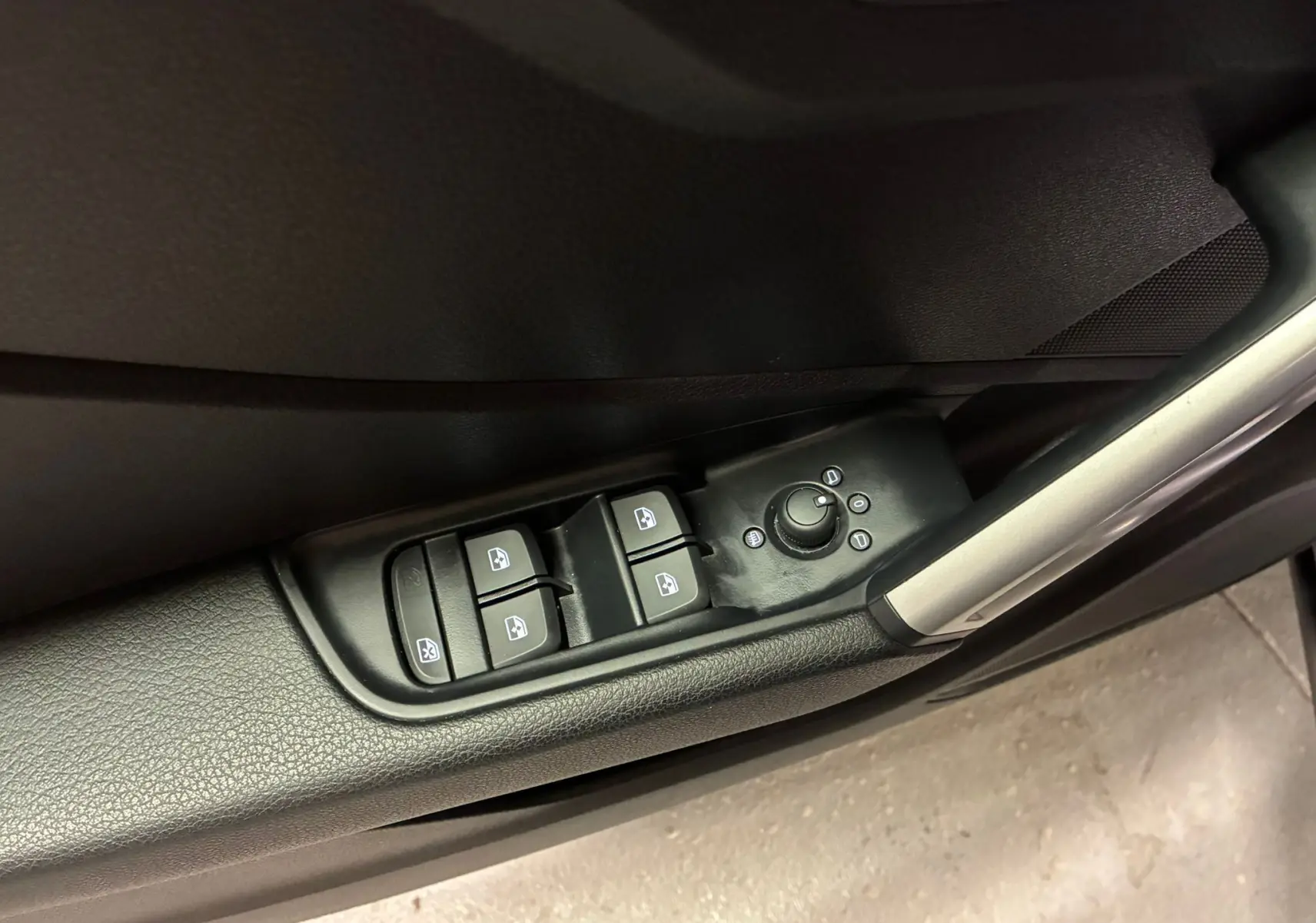 Gros plan sur les commandes des vitres et des rétroviseurs côté gauche intérieur noir de l'Audi Q2 2023 S-Line.