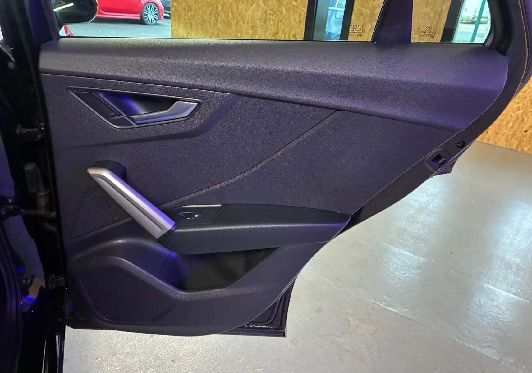 Gros plan sur la porte arrière gauche noire de l'Audi Q2 35 TFSI S-Line 2023 avec poignée argentée et habillage tissu noir.