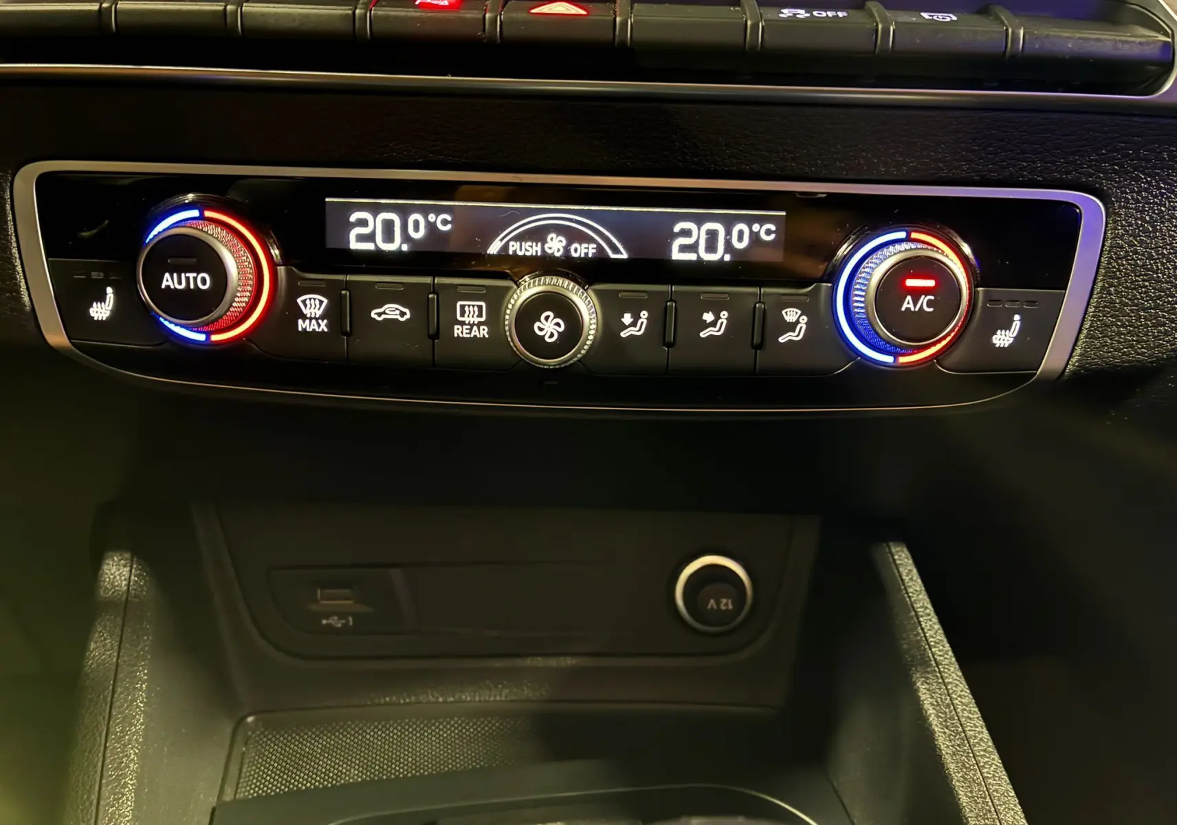 Panneau de commande de climatisation digitale de l'Audi Q2 35 TFSI noir, avec réglages à 20°C et boutons rétroéclairés rouge et bleu.