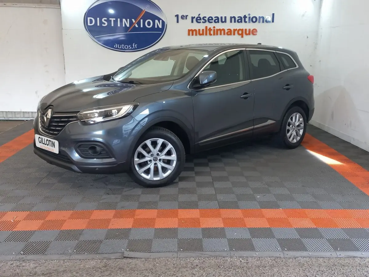 Renault Kadjar Business gris foncé en 3/4 avant droit, avec jantes alliage et phares LED visibles en intérieur showroom.