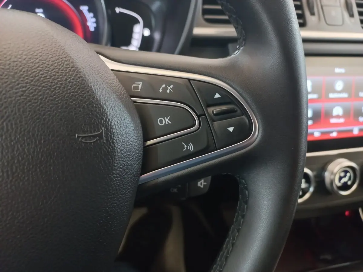 Gros plan sur la partie droite du volant noir du Renault Kadjar 2022 avec commandes vocales et écran tactile en arrière-plan.