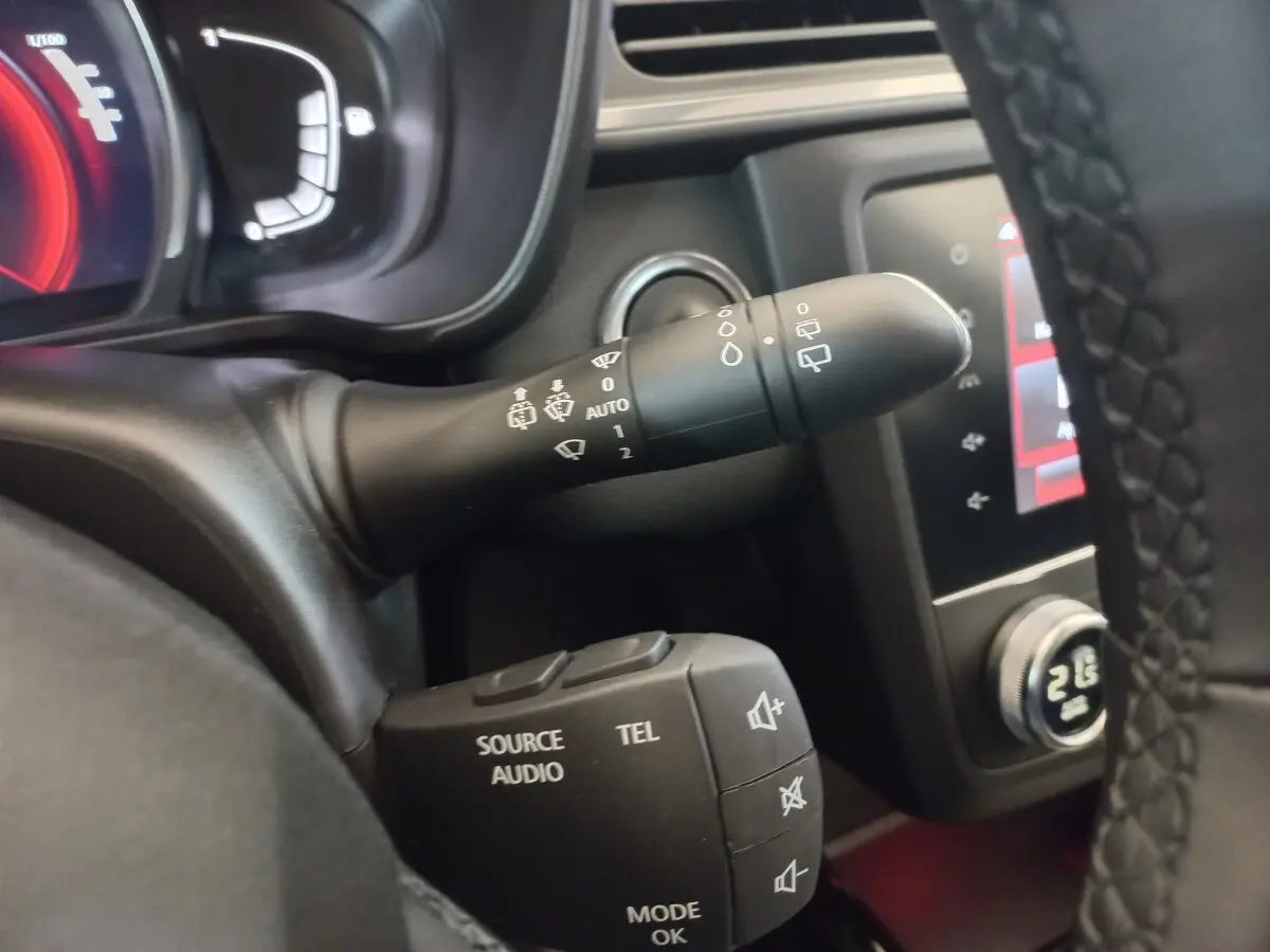 Gros plan sur les commandes au volant du Renault Kadjar gris foncé, avec affichage digital et écran tactile en arrière-plan.