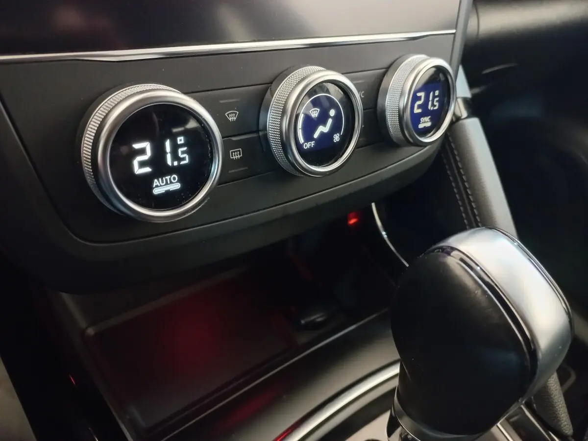 Gros plan sur la console centrale du Renault Kadjar gris foncé, montrant les commandes de climatisation digitales et le levier de vitesse automatique.
