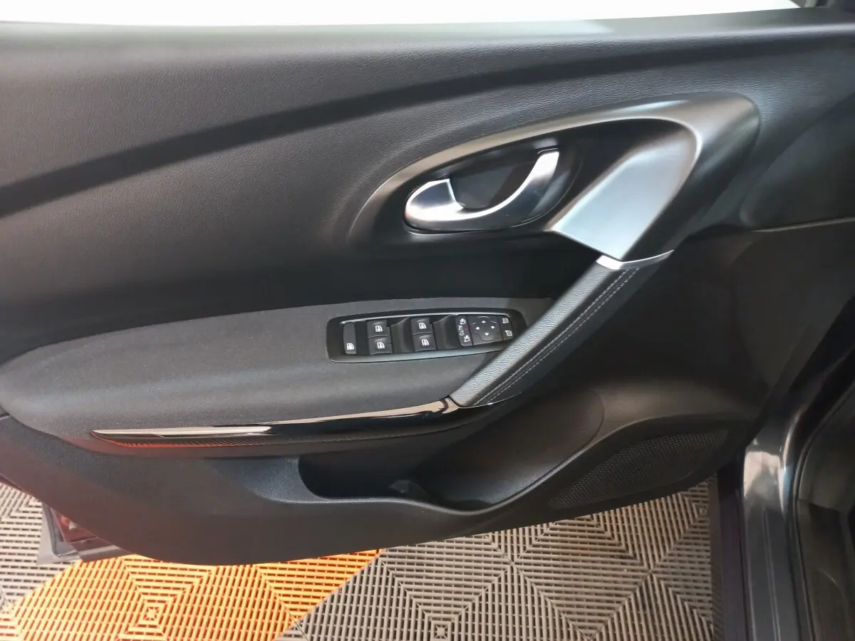 Vue rapprochée de la porte côté conducteur du Renault Kadjar gris foncé, avec commandes électriques des vitres et poignée argentée.