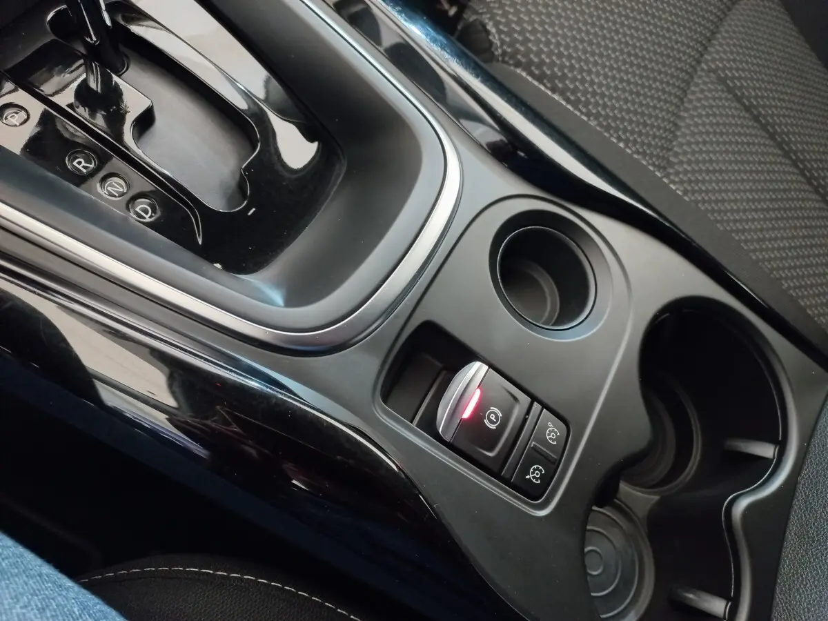 Gros plan sur la console centrale noire du Renault Kadjar 2022, montrant levier de boîte auto et boutons de frein à main électrique.