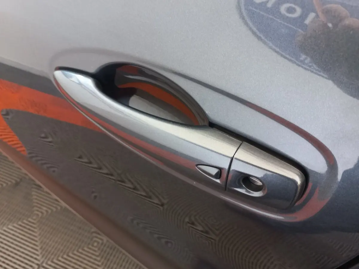 Poignée de porte gris foncé côté droit du Renault Kadjar Business Blue dCi 115 EDC 2022 avec bouton de déverrouillage.