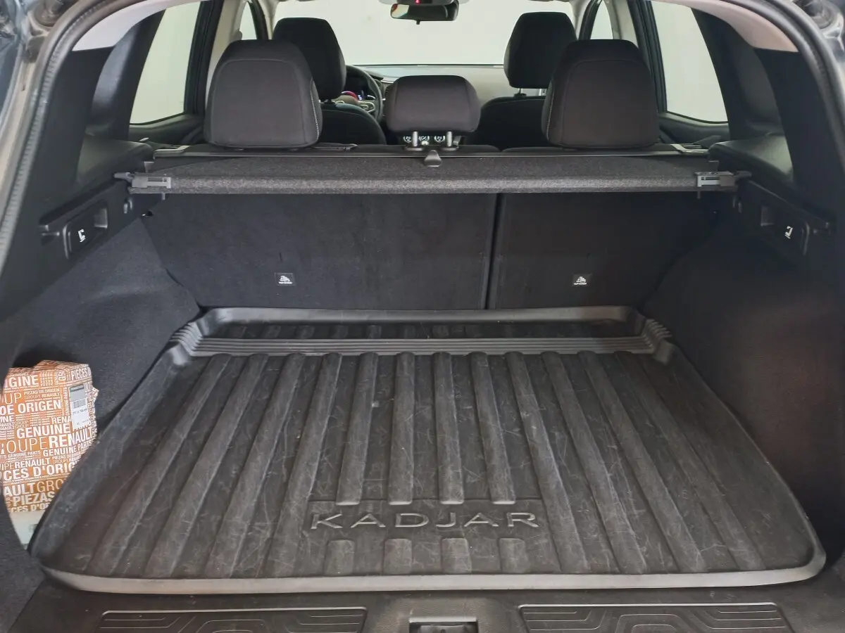 Coffre ouvert d’un Renault Kadjar gris foncé, vue arrière montrant la protection de coffre avec logo Kadjar.