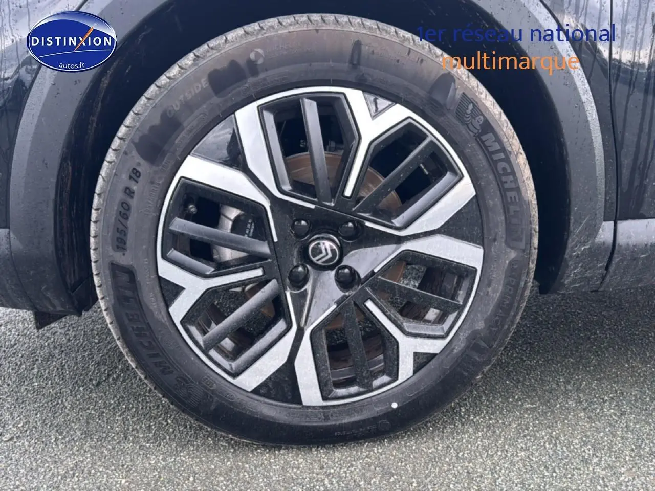 Gros plan sur la roue avant gauche noire de la Citroën C4 1.2 hybride 145 max automatique avec jante alu bicolore.