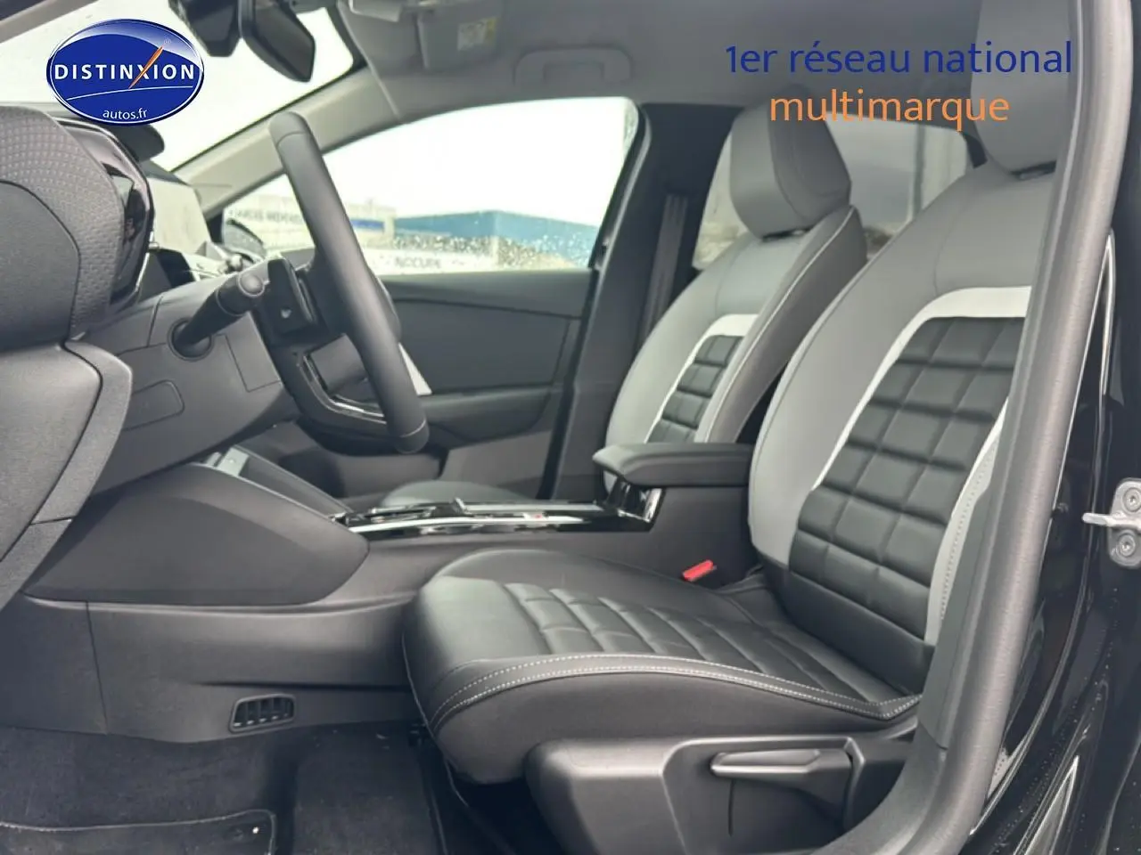 Vue intérieure côté conducteur de la Citroën C4 hybride 2025, sièges bicolores noir et gris avec accoudoir central.