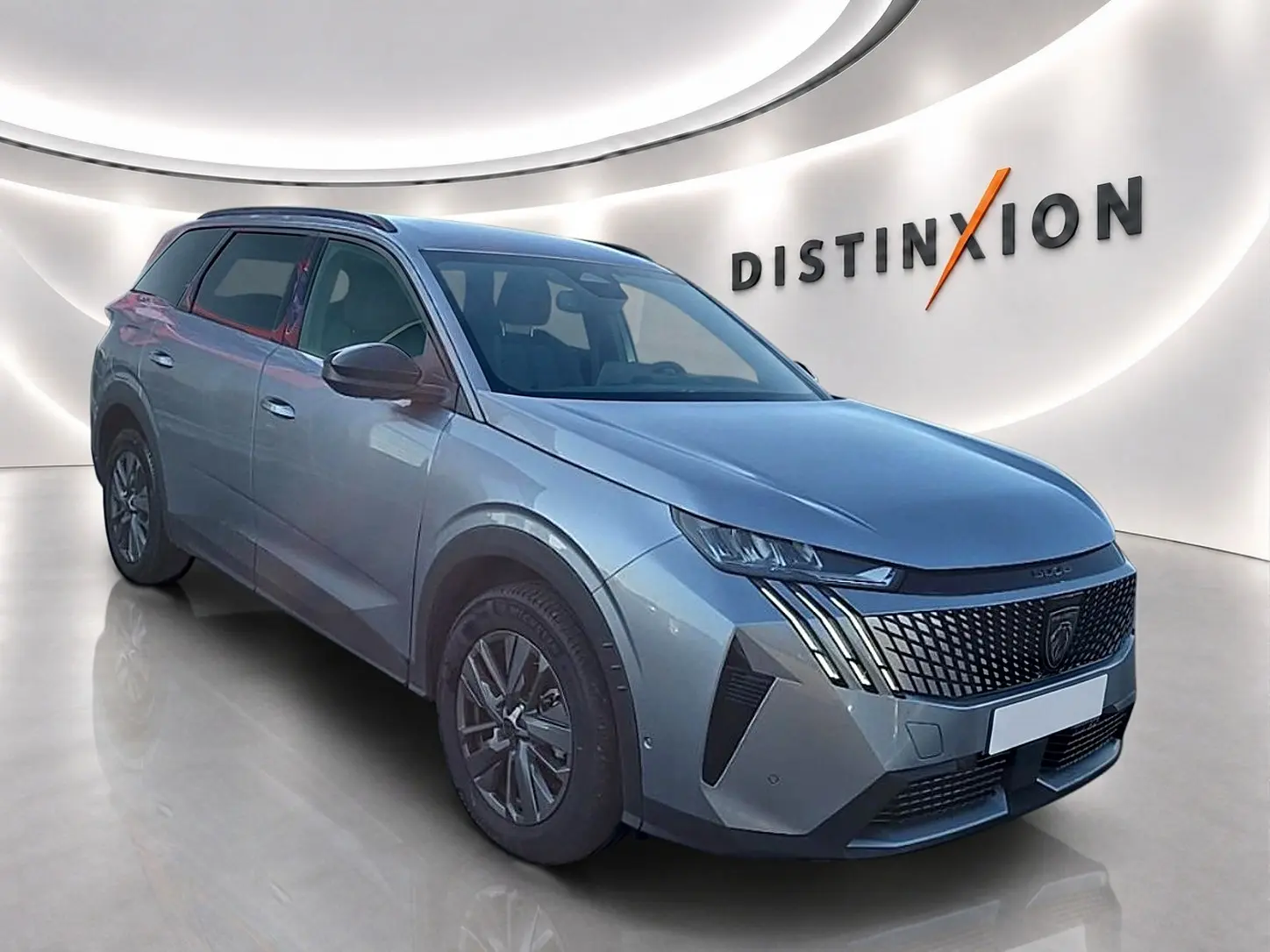 Peugeot 5008 Hybrid 145 allure gris artense en 3/4 avant droit, avec calandre distinctive et jantes alu.