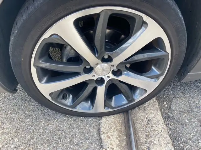 Gros plan sur la jante alliage bicolore du côté avant droit d'une Peugeot 208 gris mat de 2015.