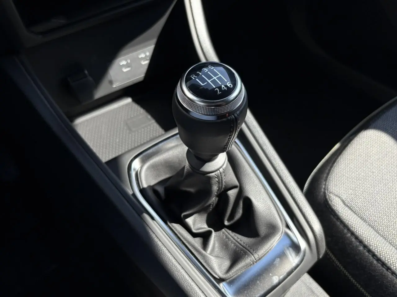 Gros plan sur le levier de vitesses manuel du Renault Captur blanc nacré 2025, entouré de cuir noir et chrome.