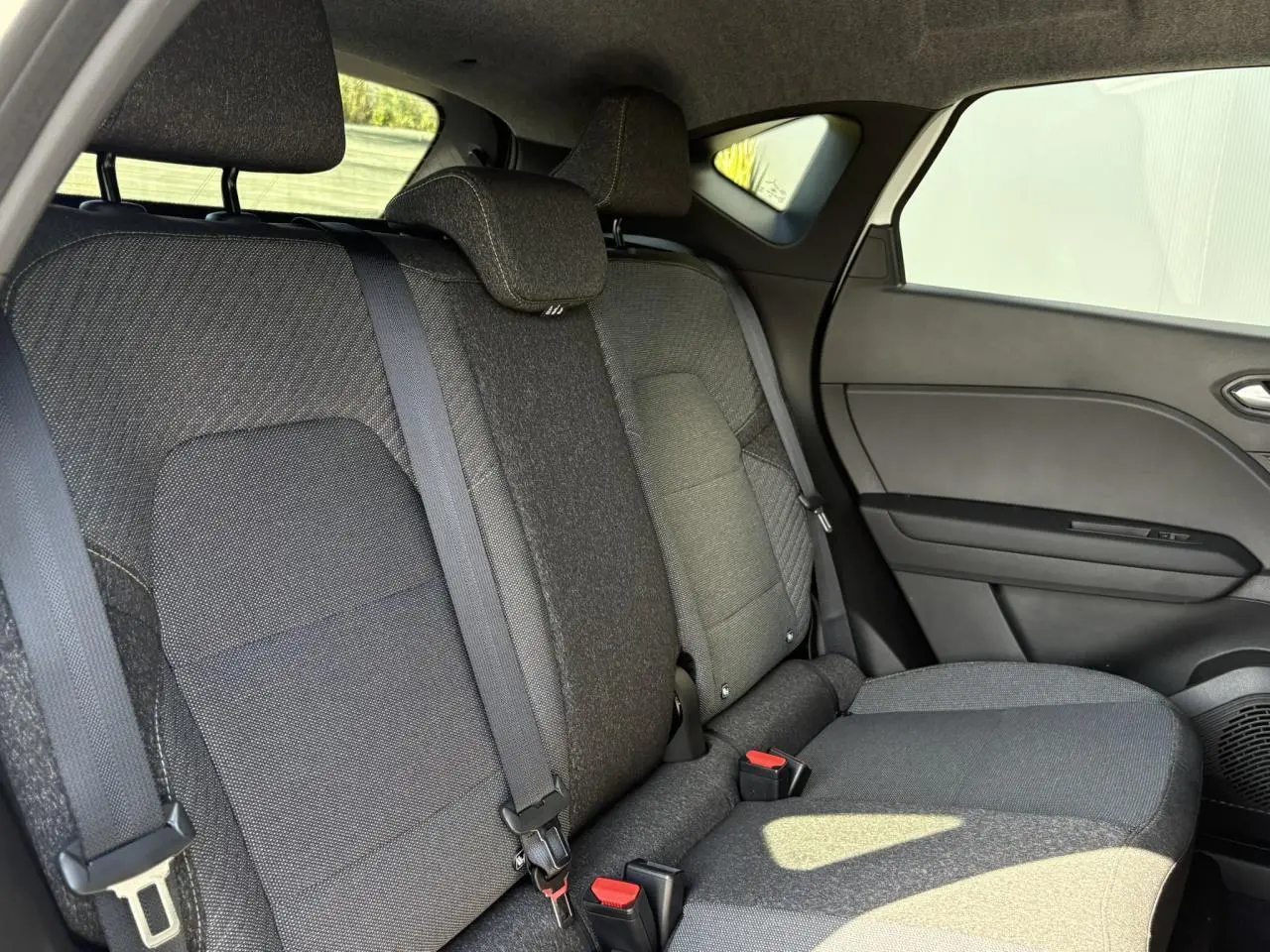 Vue latérale droite de la banquette arrière noire du Renault Captur 2025 avec ceintures et appuis-tête intégrés.