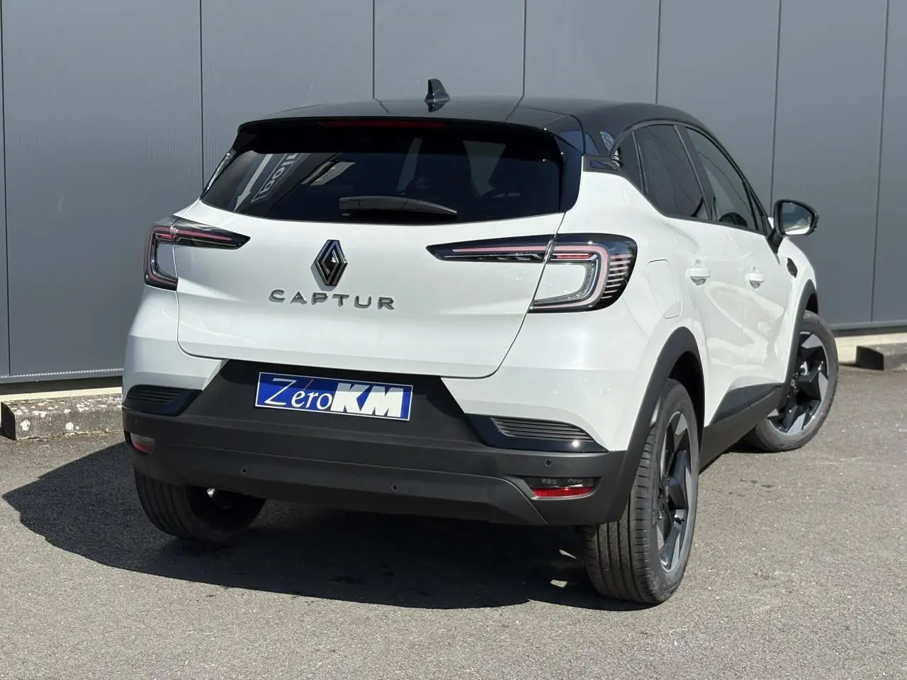 Vue 3/4 arrière droite du Renault Captur blanc nacré avec toit noir étoilé et jantes aluminium 18 pouces.