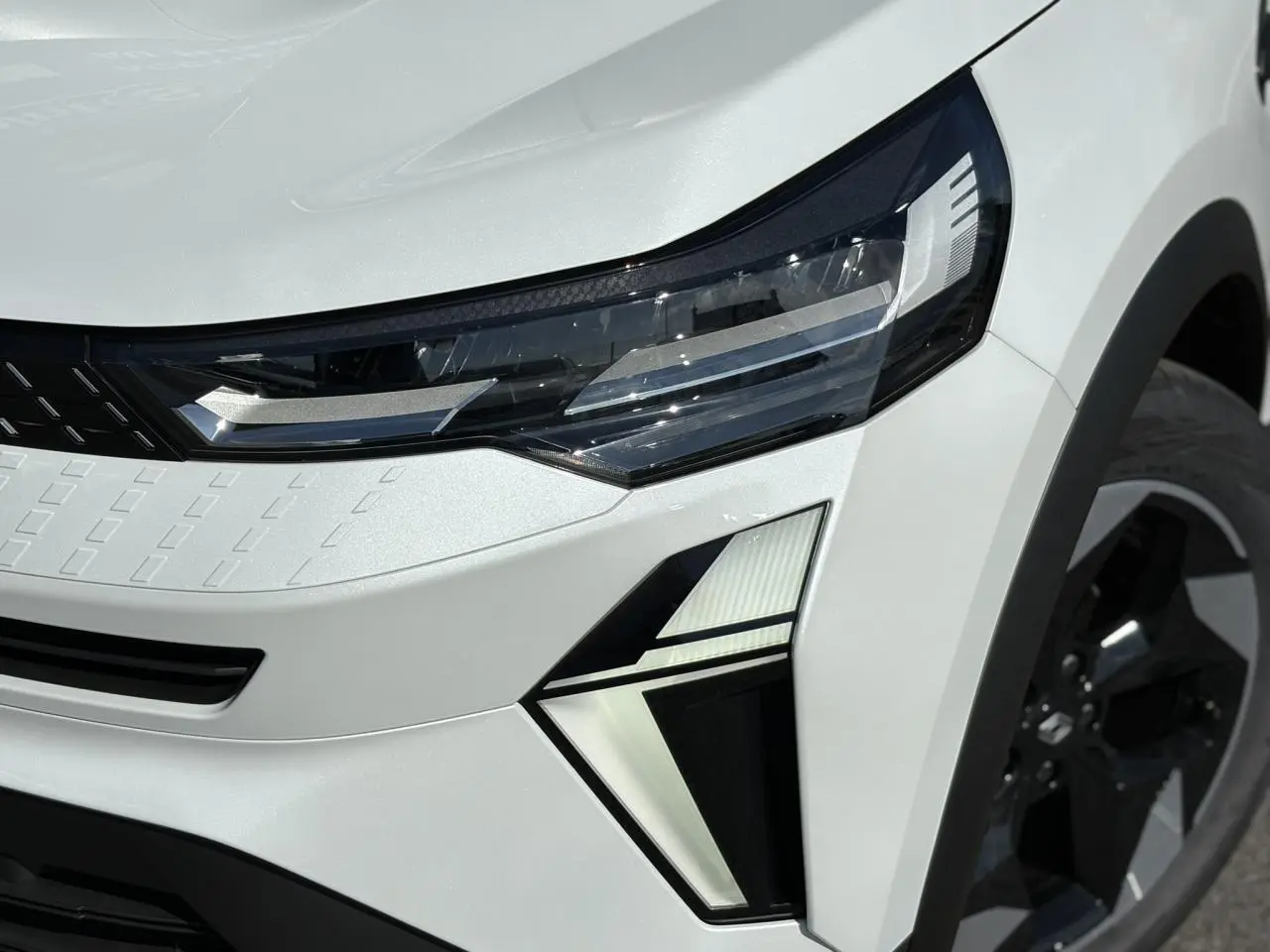 Gros plan sur le phare avant droit du Renault Captur Blanc Nacré 2025 avec jante aluminium noire.