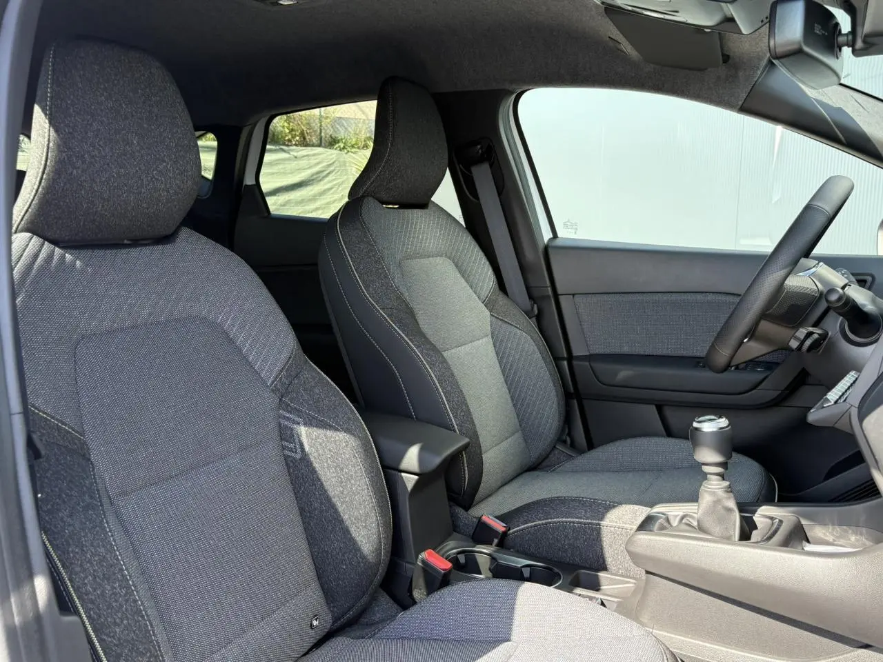 Vue intérieure côté droit du Renault Captur 2025, sièges tissu gris et levier de vitesses manuel visible.
