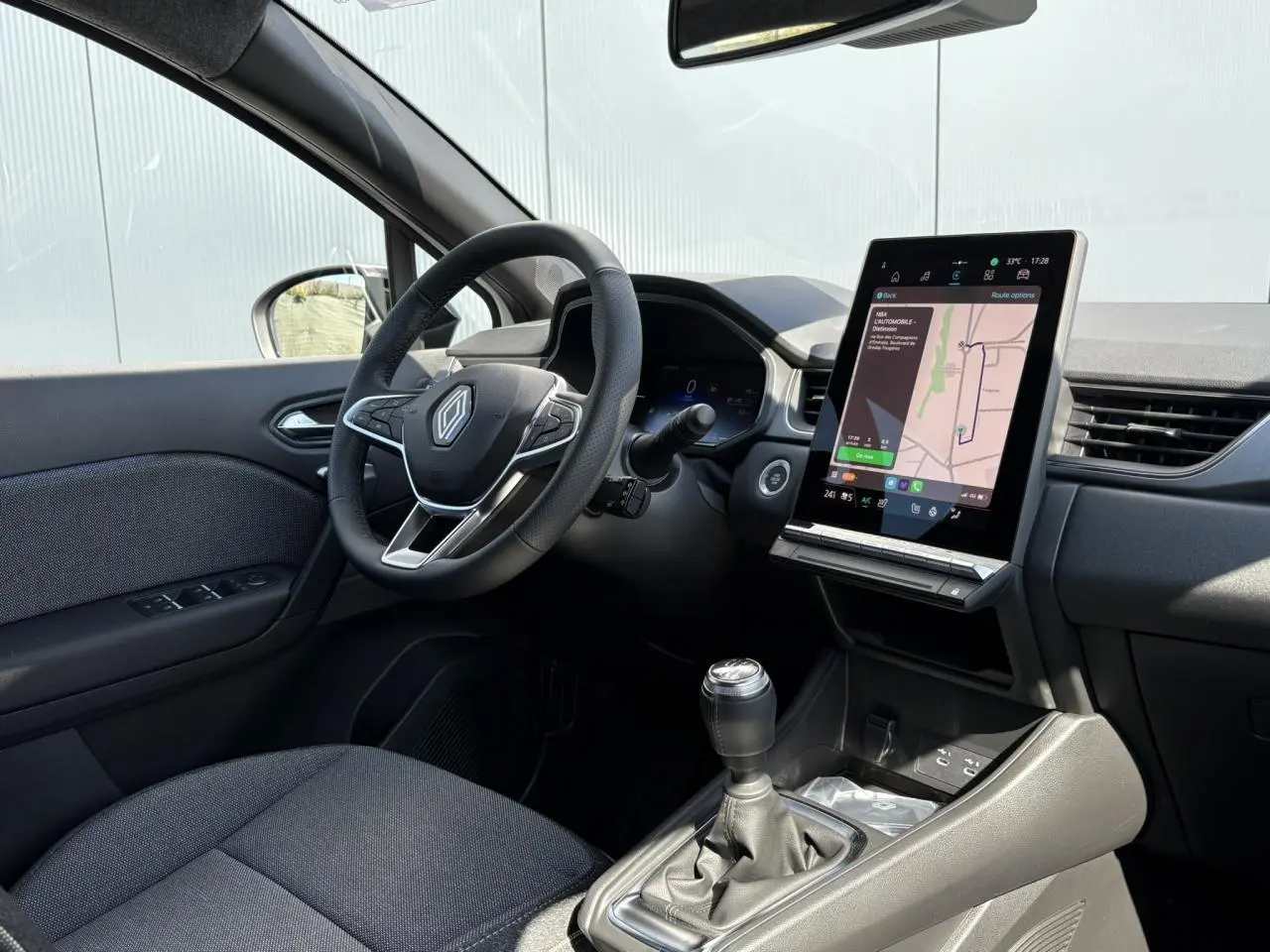 Intérieur côté conducteur du Renault Captur 2025 avec volant multifonction, boîte manuelle et écran tactile vertical.