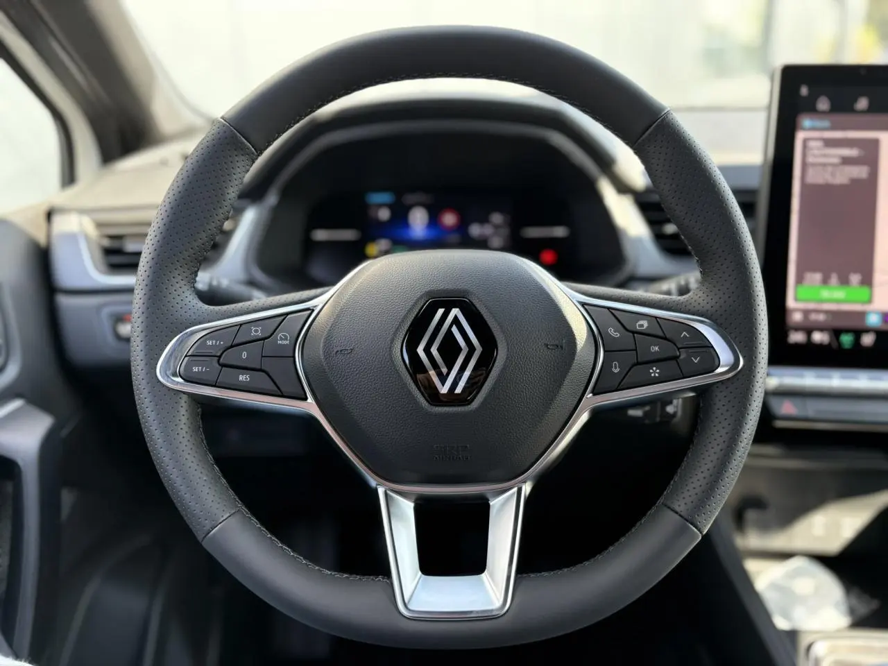 Volant en cuir noir avec commandes intégrées et logo Renault au centre, intérieur du Renault Captur 2025.