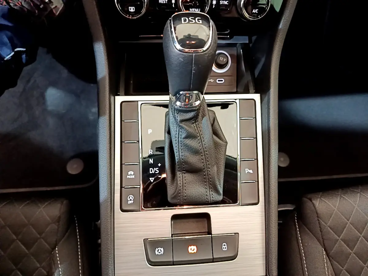 Le levier de vitesse DSG noir et chrome de la Skoda Superb 2020, vu de dessus, entouré de commandes sur console bois clair.