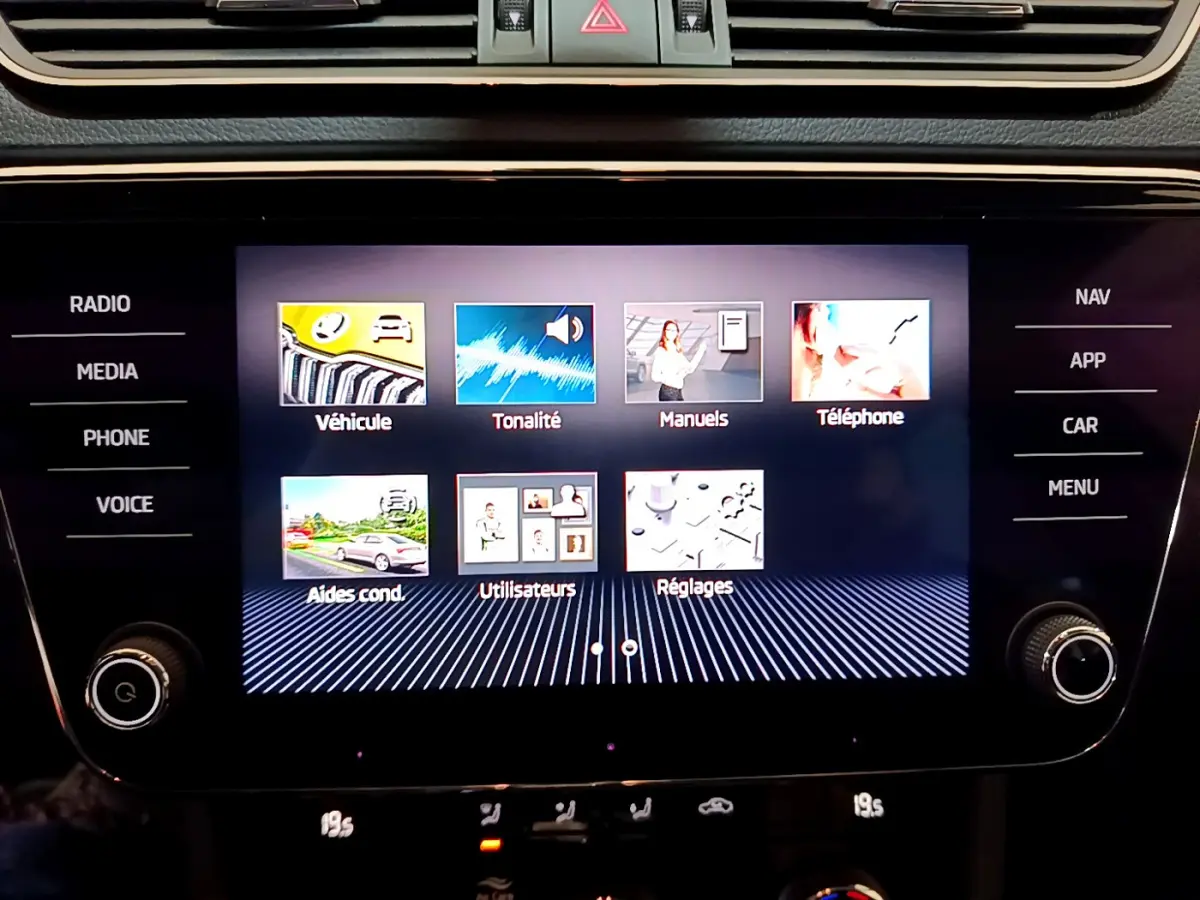 Écran tactile central affichant le menu multimédia de la Skoda Superb 2020, avec commandes autour et finition noire brillante.