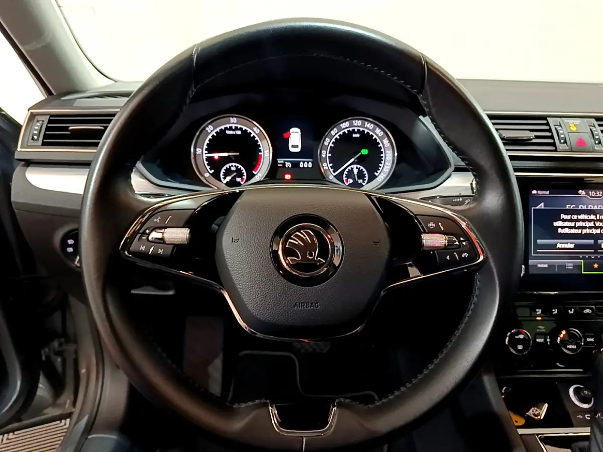 Vue centrée sur le volant cuir noir de la Skoda Superb 2020, avec tableau de bord digital et écran tactile visible à droite.