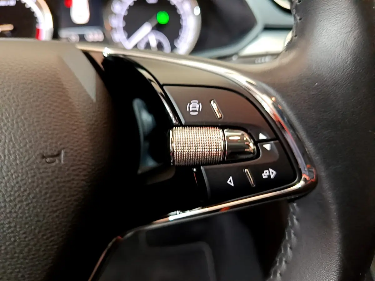 Gros plan sur les commandes à droite du volant cuir d'une Skoda Superb 2020, avec molette métallique et boutons noirs.