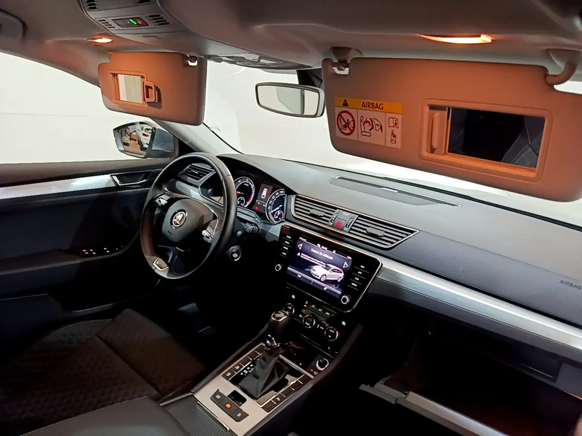 Intérieur noir de la Skoda Superb 2020 vu côté conducteur, avec tableau de bord et écran tactile central allumés.