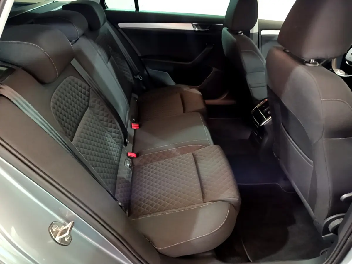 Vue intérieure côté arrière droit de la Skoda Superb 2020 gris clair, sièges arrière en tissu noir matelassé avec surpiqûres.