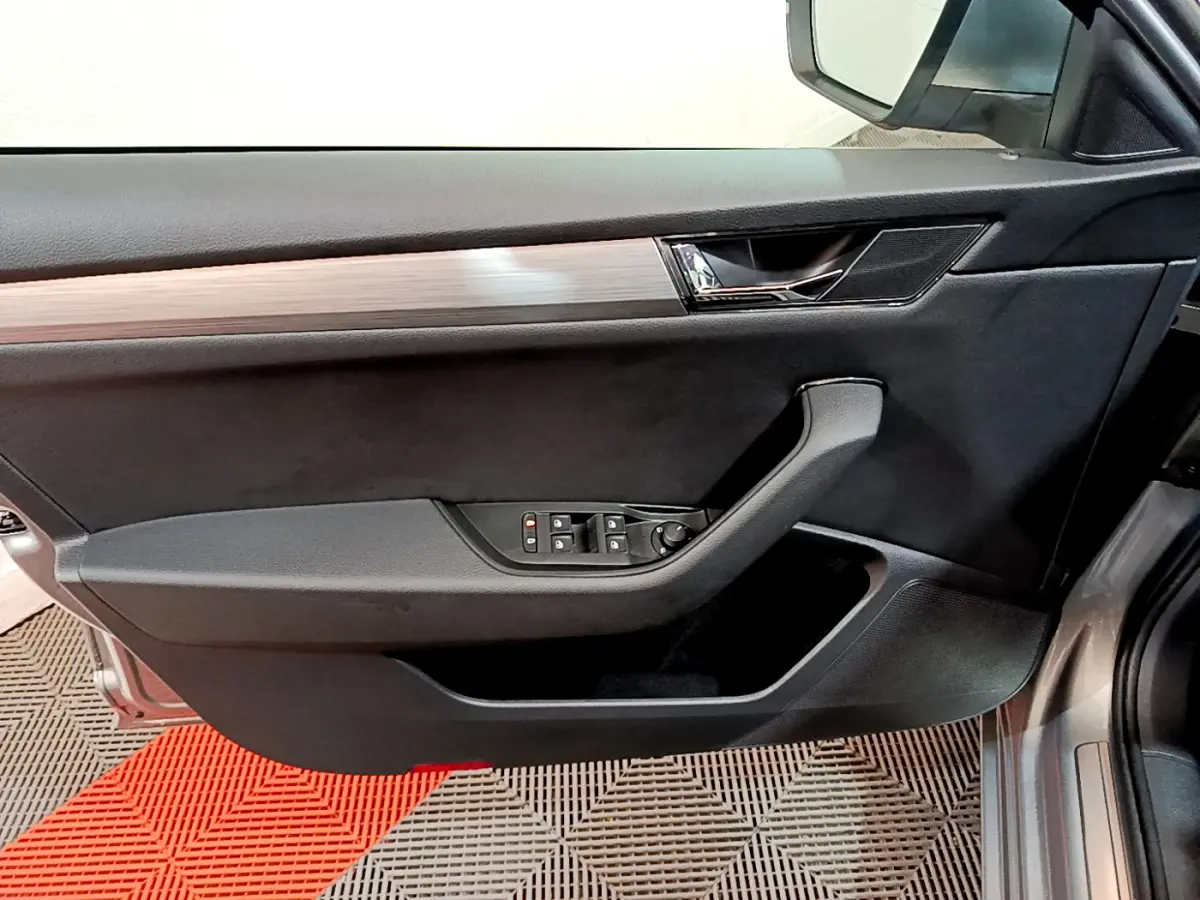 Vue côté gauche de la porte avant gris clair d'une Skoda Superb 2020 avec commandes électriques des vitres et insert bois.