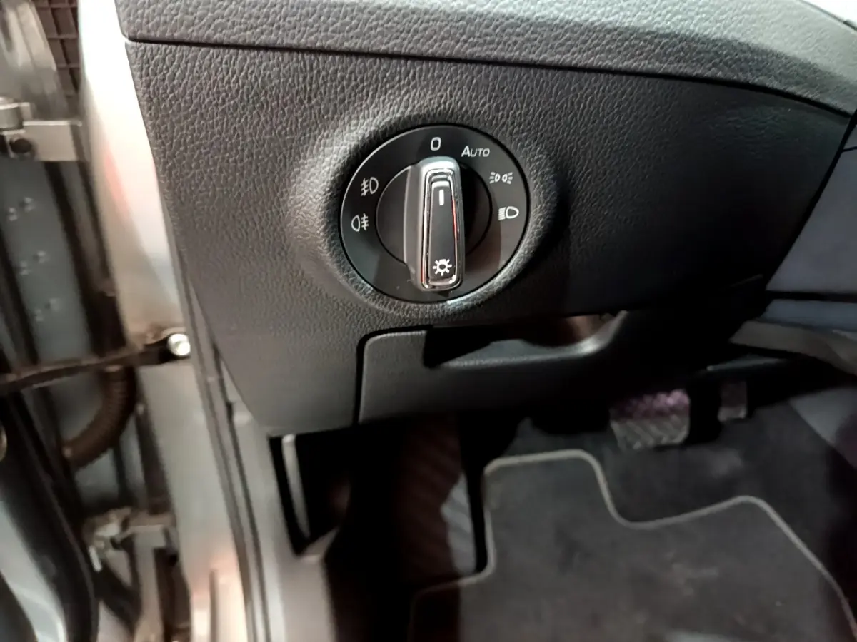 Gros plan sur la commande des phares à gauche du volant dans l'habitacle gris foncé de la Skoda Superb 2020.