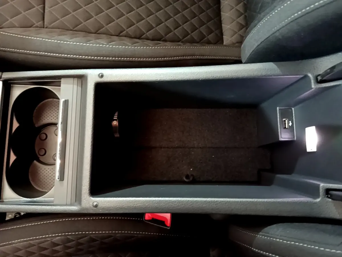 Vue plongeante sur le rangement central et porte-gobelets avec USB de la Skoda Superb gris clair 2020 intérieur cuir noir.