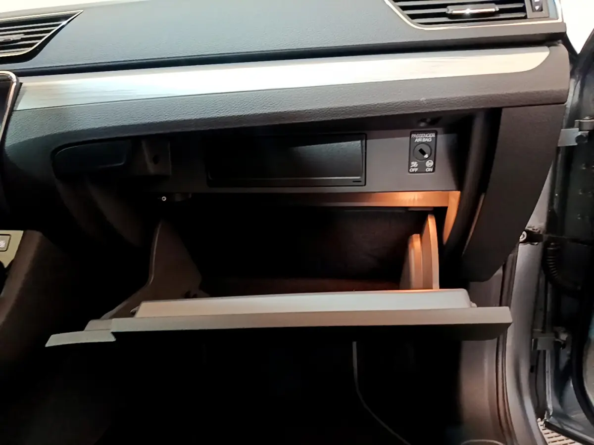 Gros plan sur la boîte à gants ouverte côté passager d'une Skoda Superb gris clair avec éclairage intérieur doux.