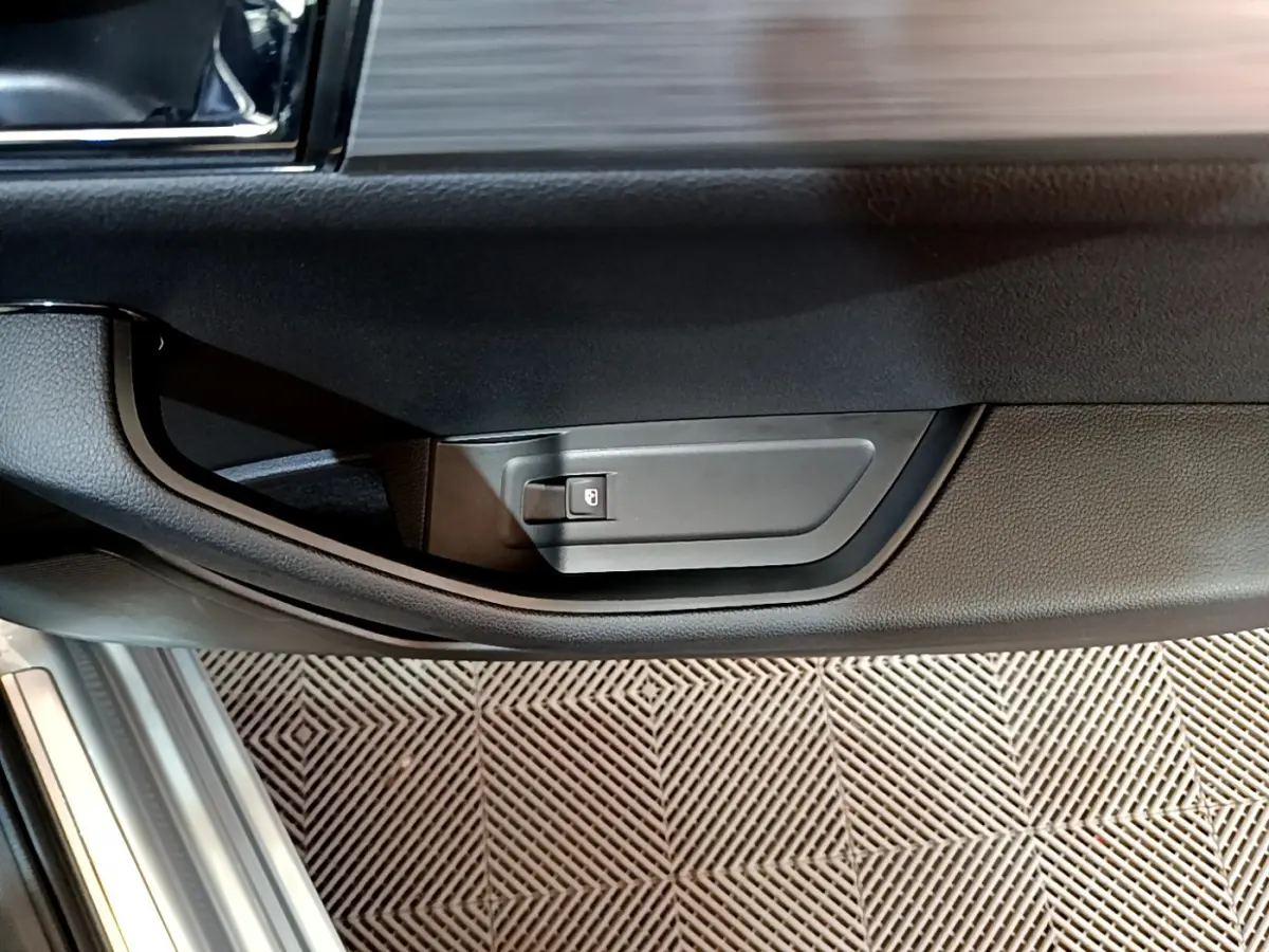 Gros plan sur la poignée intérieure de porte côté conducteur d'une Skoda Superb gris clair, avec bouton de verrouillage.