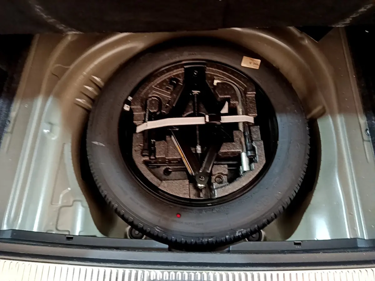 Vue plongeante sur la roue de secours et le kit d'outils dans le coffre gris clair d'une Skoda Superb 2020.
