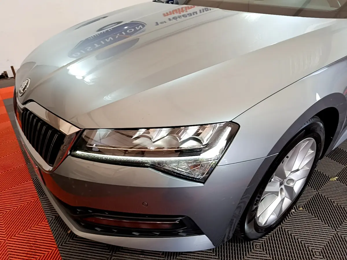 Vue 3/4 avant droit d'une Skoda Superb gris clair mettant en valeur ses phares LED et sa calandre chromée.