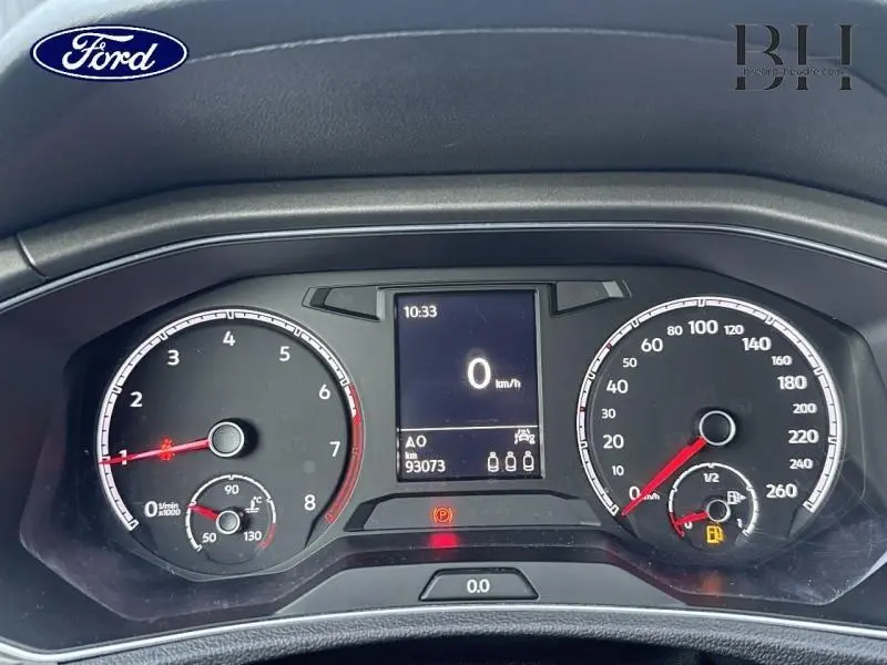 Tableau de bord avec compte-tours et compteur de vitesse, affichage digital au centre, éclairage rouge et noir.