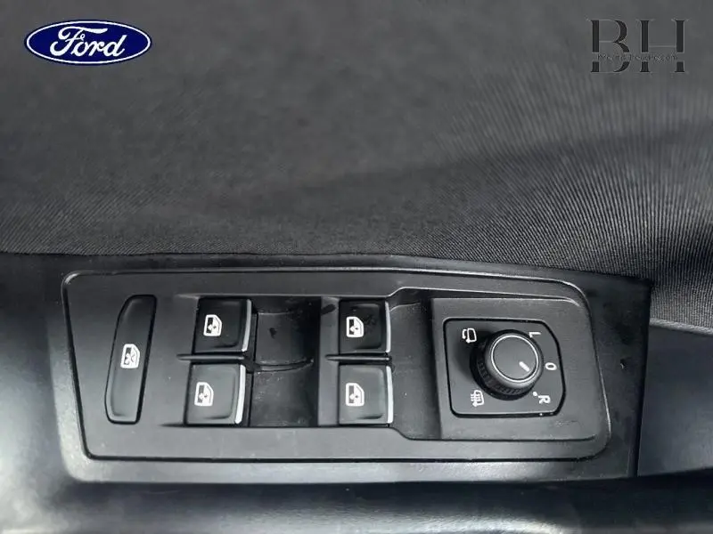 Gros plan sur les commandes des vitres électriques et des rétroviseurs d'un Volkswagen T-Roc bleu Ravenna métallisé.