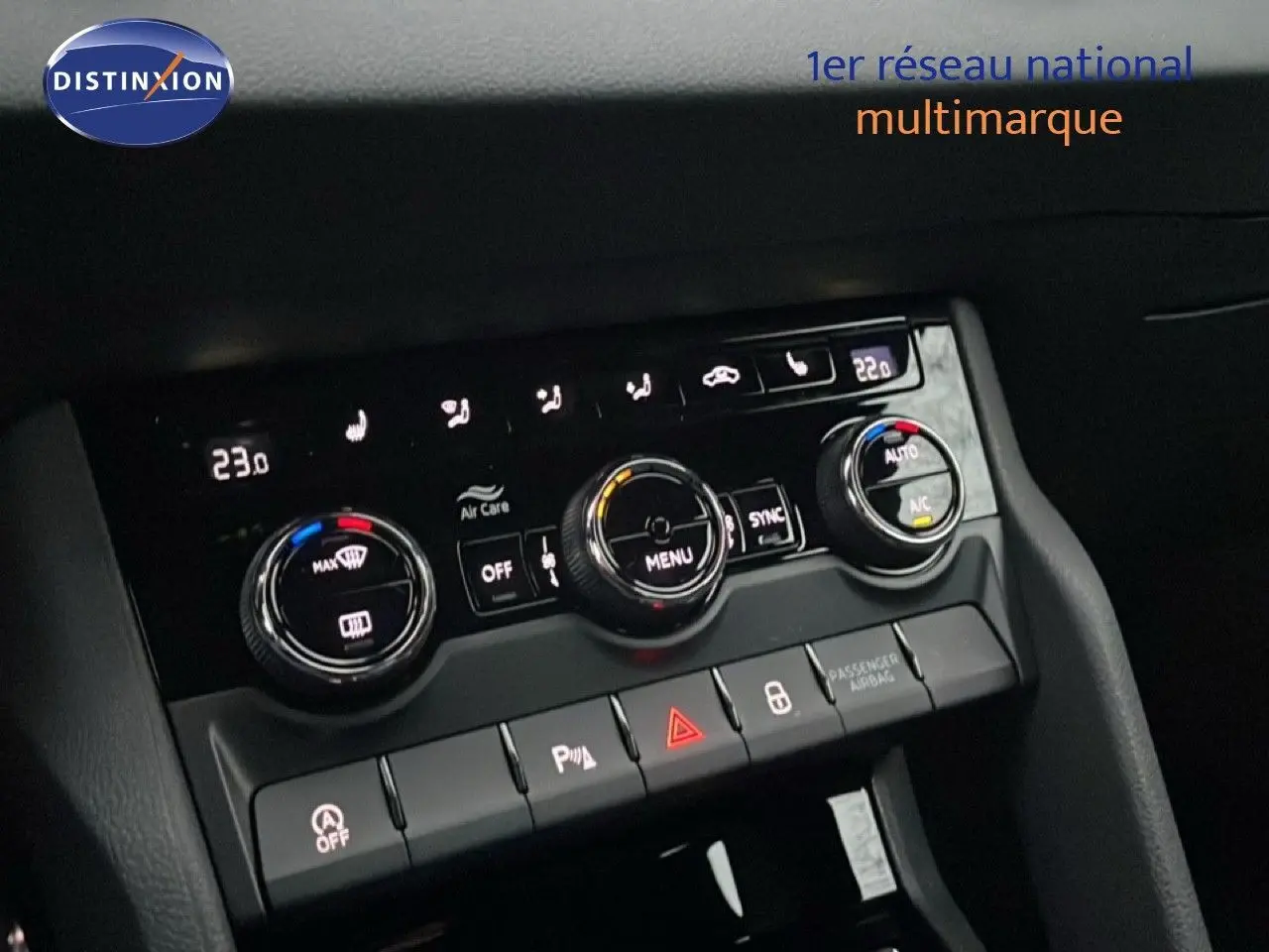 Détail du tableau de bord du Skoda Karoq gris argent, montrant les commandes de climatisation et les boutons de sécurité.