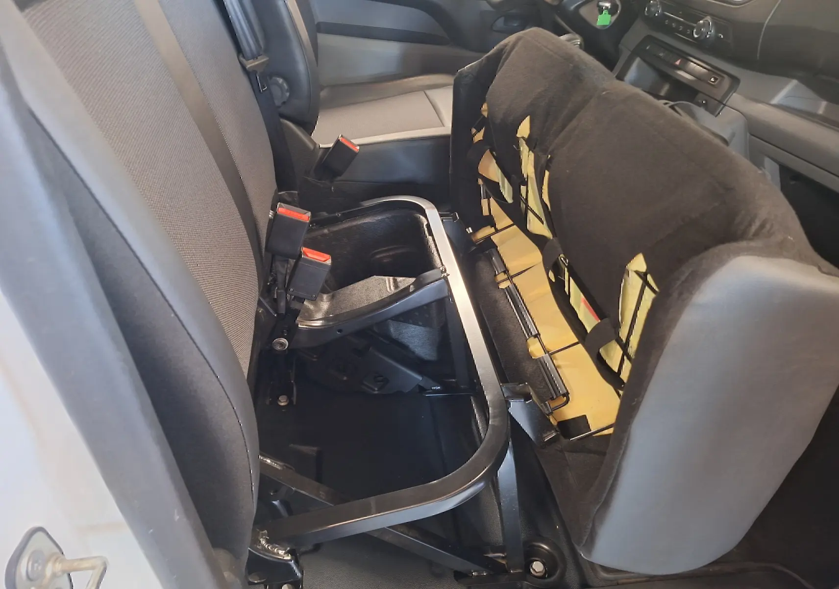Vue intérieure côté passager du siège avant relevé du Citroën Jumpy blanc, montrant la structure métallique et le rangement dessous.