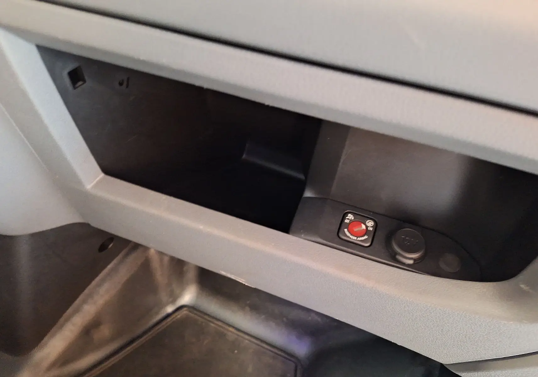 Gros plan sur le compartiment de rangement intérieur du Citroën Jumpy blanc avec bouton de commande et prise 12V visible.