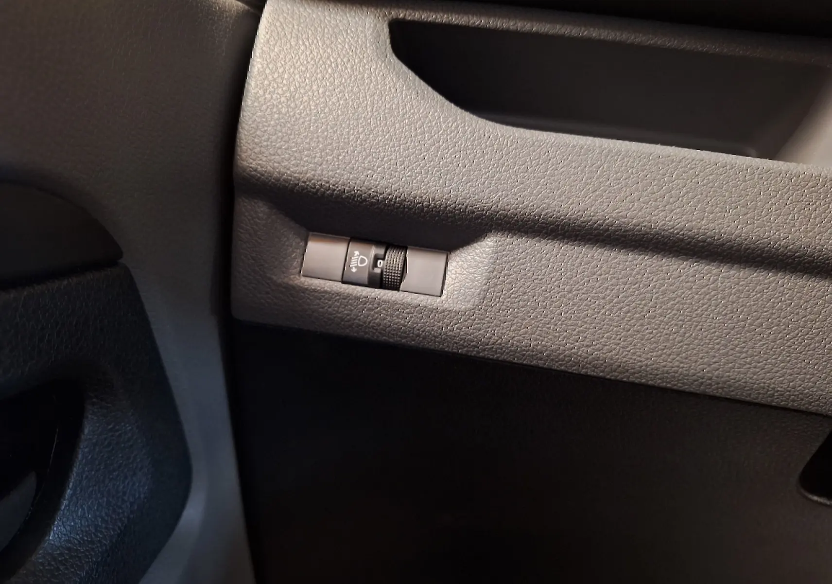 Gros plan sur le réglage d'intensité des phares dans l'habitacle gris foncé du Citroën Jumpy blanc 2020 côté gauche.