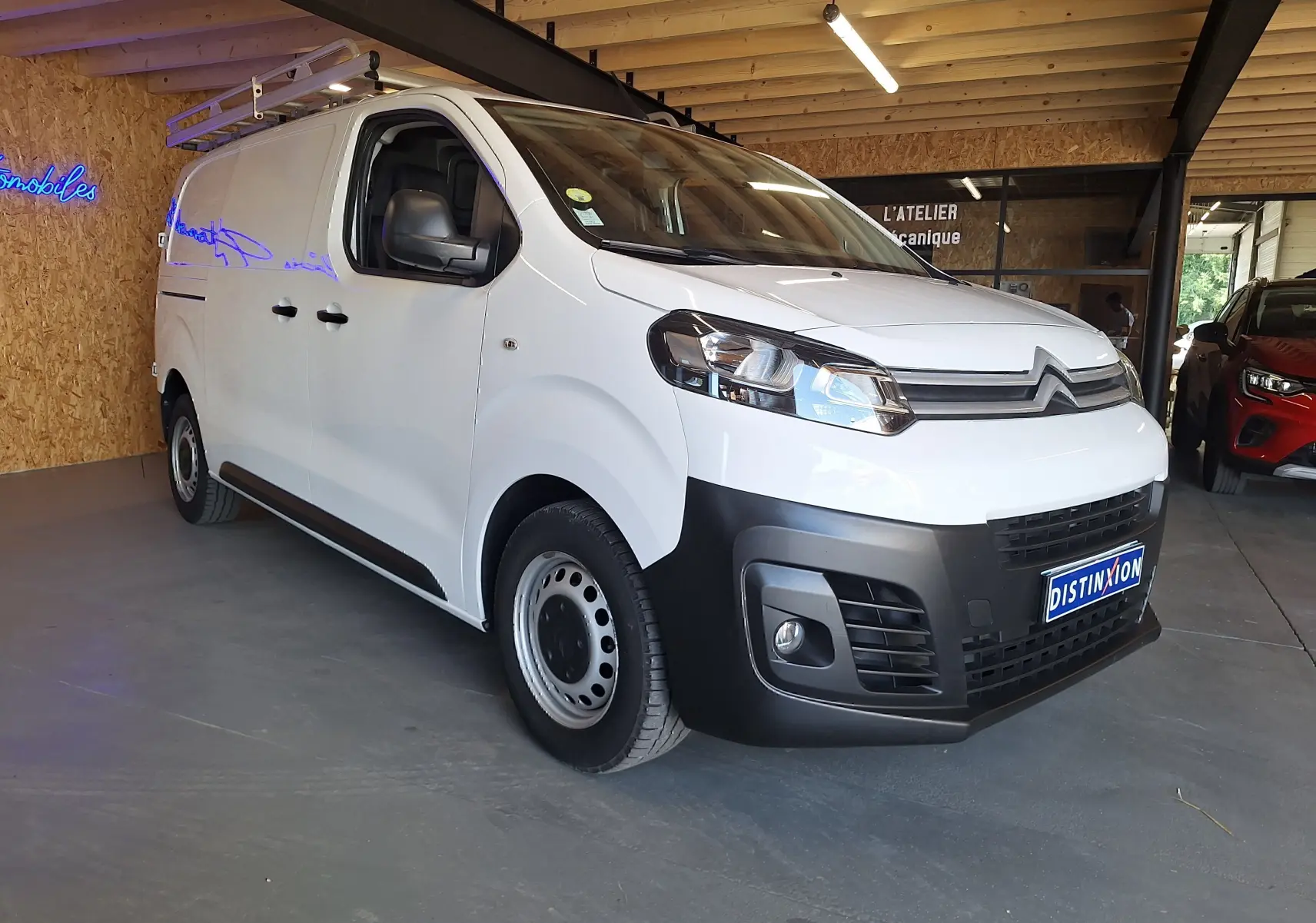 Vue 3/4 avant droite d'un utilitaire Citroën Jumpy blanc 2020 avec galerie de toit et pare-chocs noir.