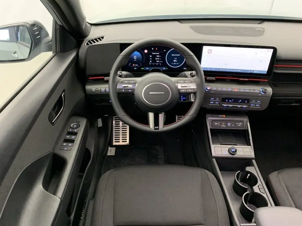 Vue intérieure frontale du tableau de bord du Hyundai Kona Hybrid 2025, avec écran numérique et volant multifonction.