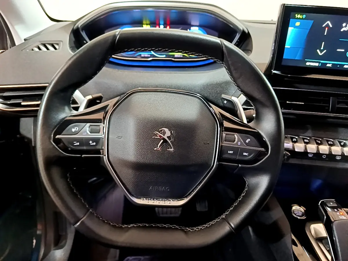 Vue rapprochée du volant cuir noir de la Peugeot 3008 bleu, avec tableau de bord numérique et écran tactile visible.