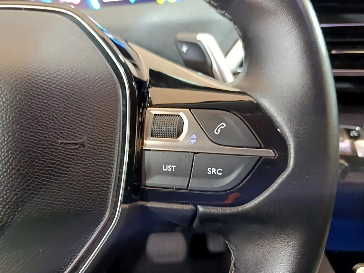 Gros plan sur les commandes du volant cuir noir du Peugeot 3008 hybride rechargeable bleu, version Allure Pack 2021.